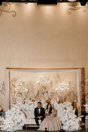 Romantic wedding setup with crystal chandeliers and white floral arch creating an elegant atmosphere.