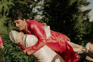 Playful moment captured between wedding couple in red and white attire.