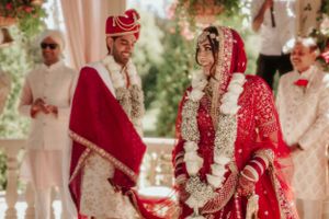 Traditional Indian wedding ceremony with bride and groom wearing red and cream traditional attire.