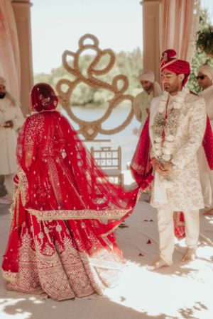 Wedding ceremony in outdoor pavilion with ornate heart-shaped decor backdrop.