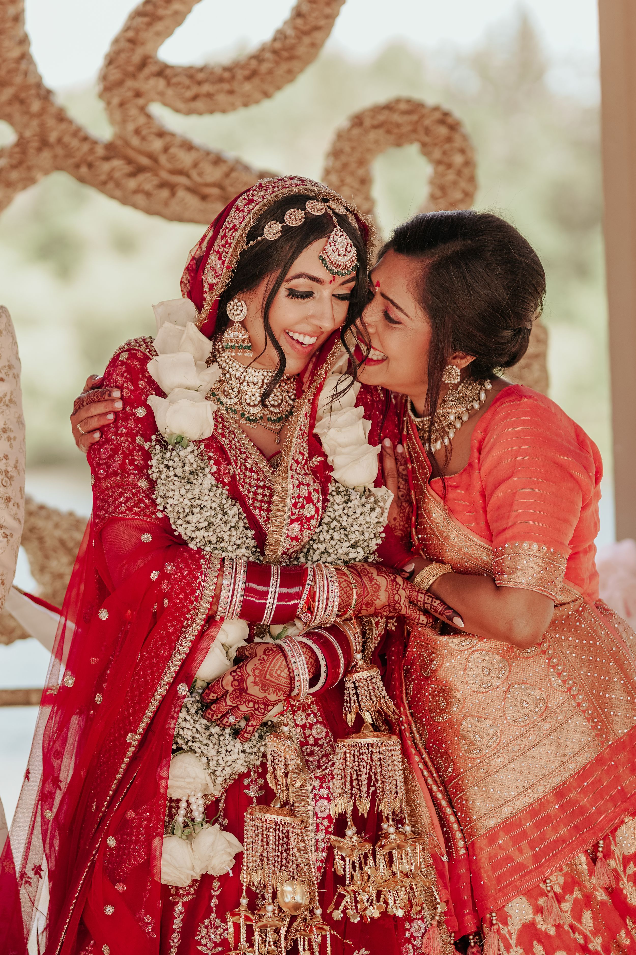 Two people in traditional Indian wedding attire sharing a joyful moment together.