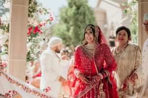 Traditional Indian wedding entrance with red floral decorations and cream pillars.