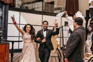 Newlyweds making a grand entrance at their reception with celebratory gestures.