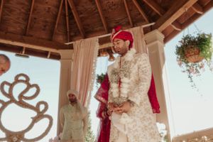A traditional Indian wedding ceremony taking place under a wooden gazebo with decorative elements.