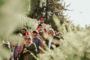 Candid shot of wedding guests celebrating outdoors through foliage.