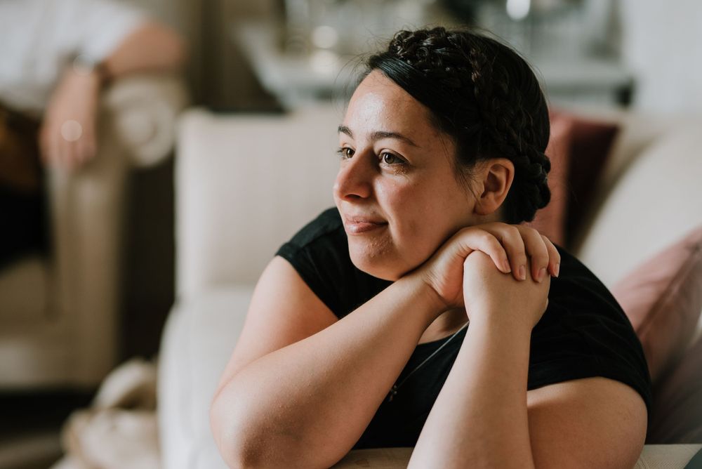 Person in black shirt resting their hand on their neck while looking to the side.