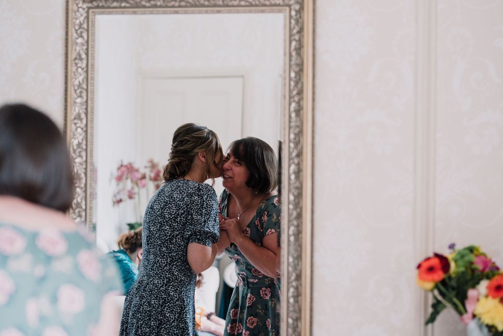 Two people sharing an intimate moment reflected in an ornate framed mirror.