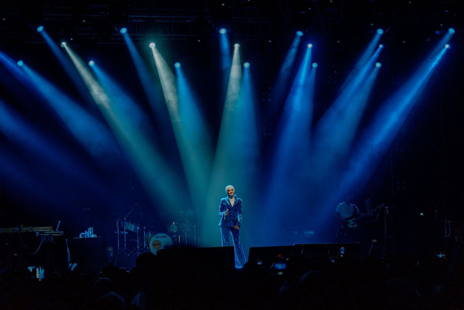 Concert stage illuminated by dramatic blue spotlights creating an atmospheric performance setting.