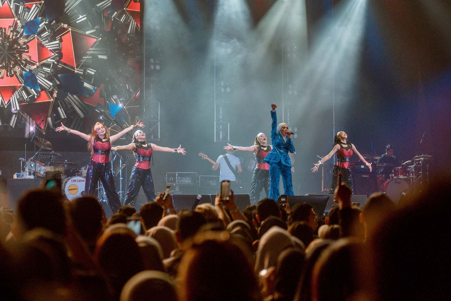 Energetic concert performance with crowd silhouettes and dramatic stage lighting effects.