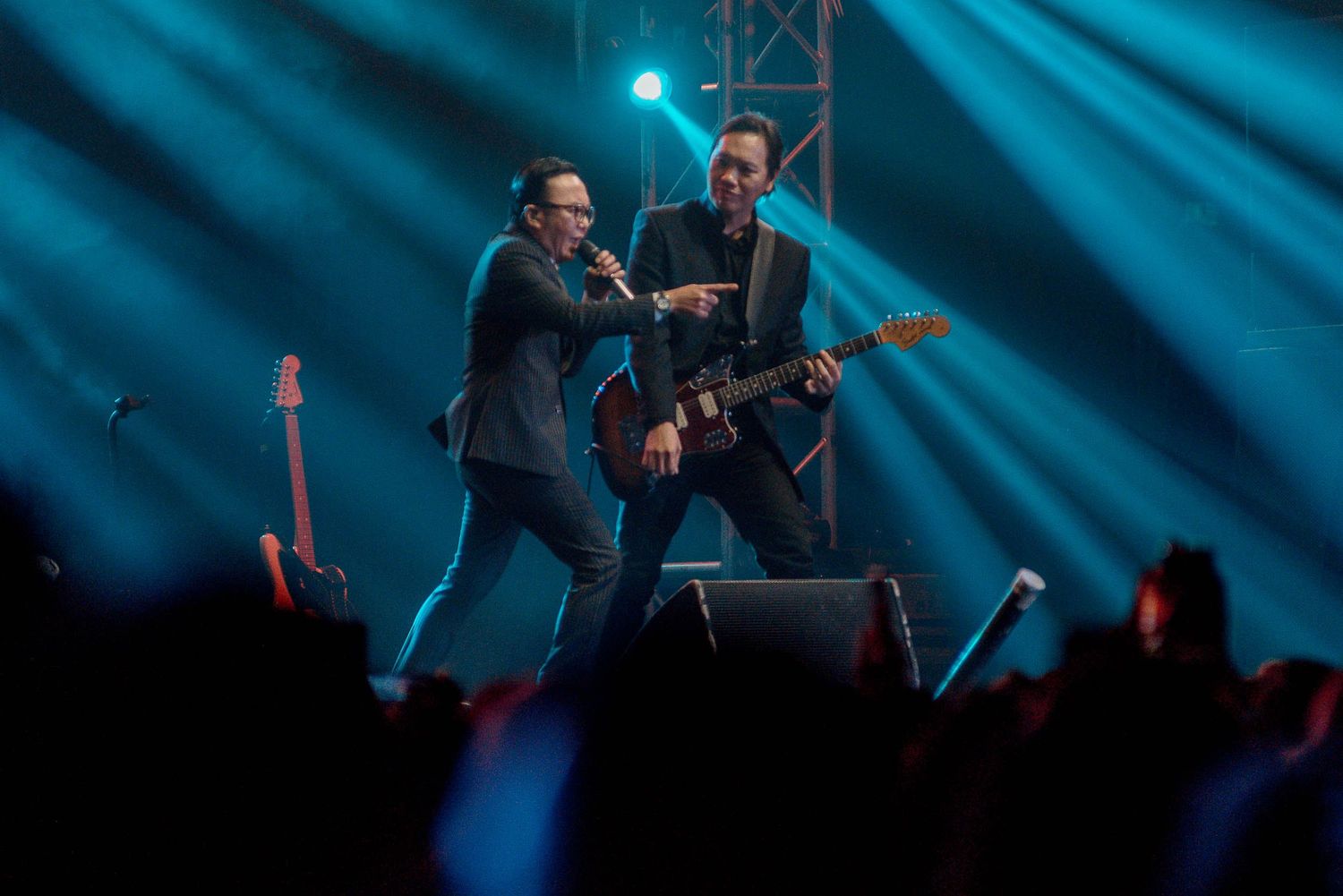 Two performers energetically entertaining on stage with dramatic blue lighting effects.