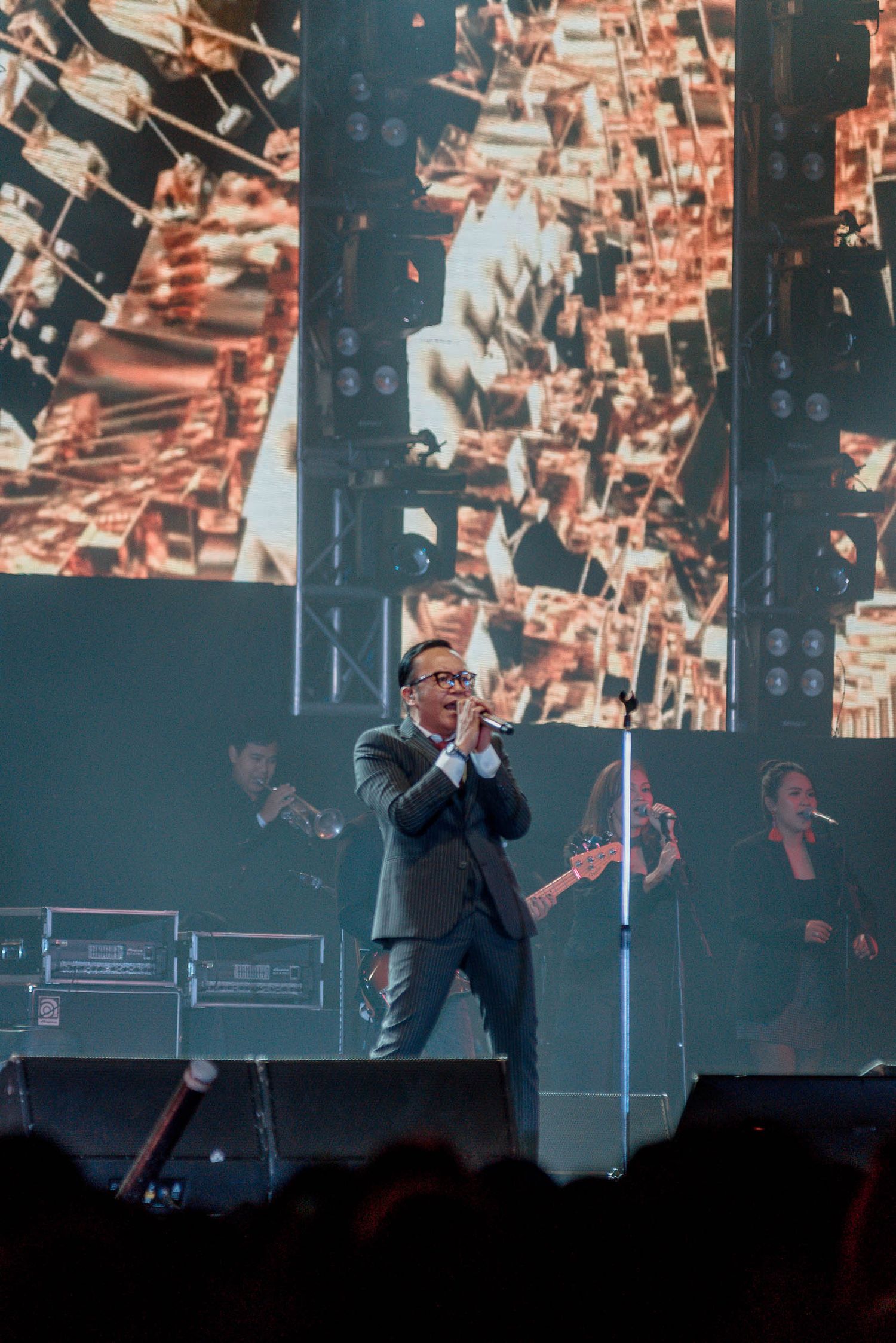 A performer on stage with abstract digital art projections in the background.