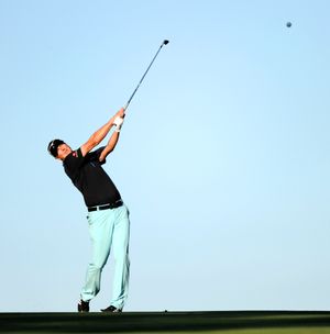 Golf player follows through after hitting ball in the air