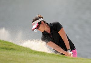 Lady playing golf shot from bunker