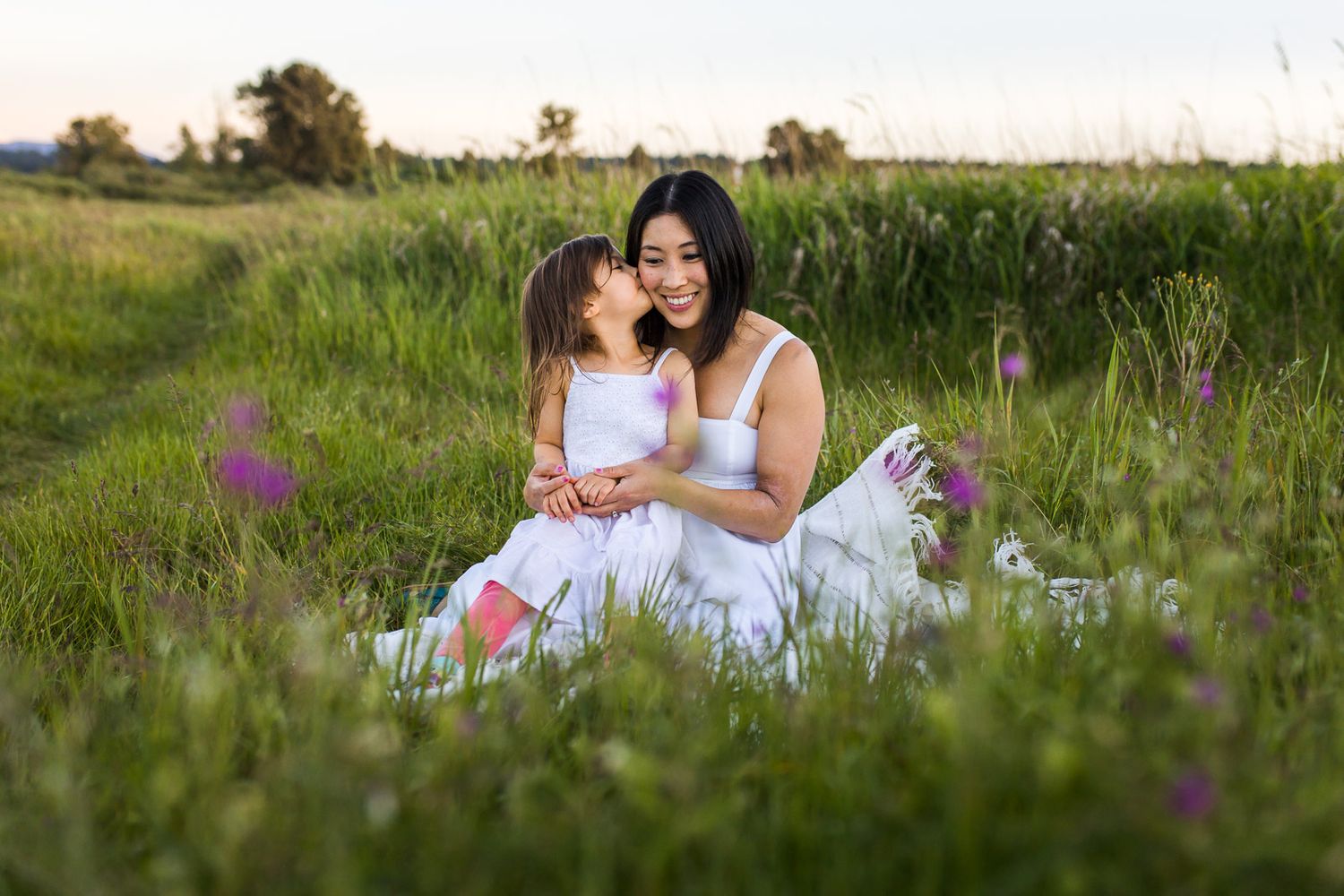 Mother daughter sharing a hug and kiss on a blanket
