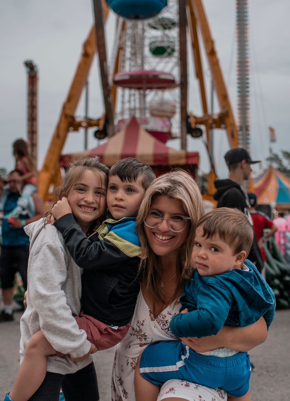 People enjoying a carnival with colorful rides and amusement park attractions in the background.