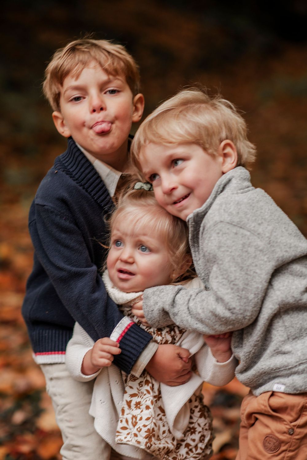 Three children sharing a playful moment together during autumn.