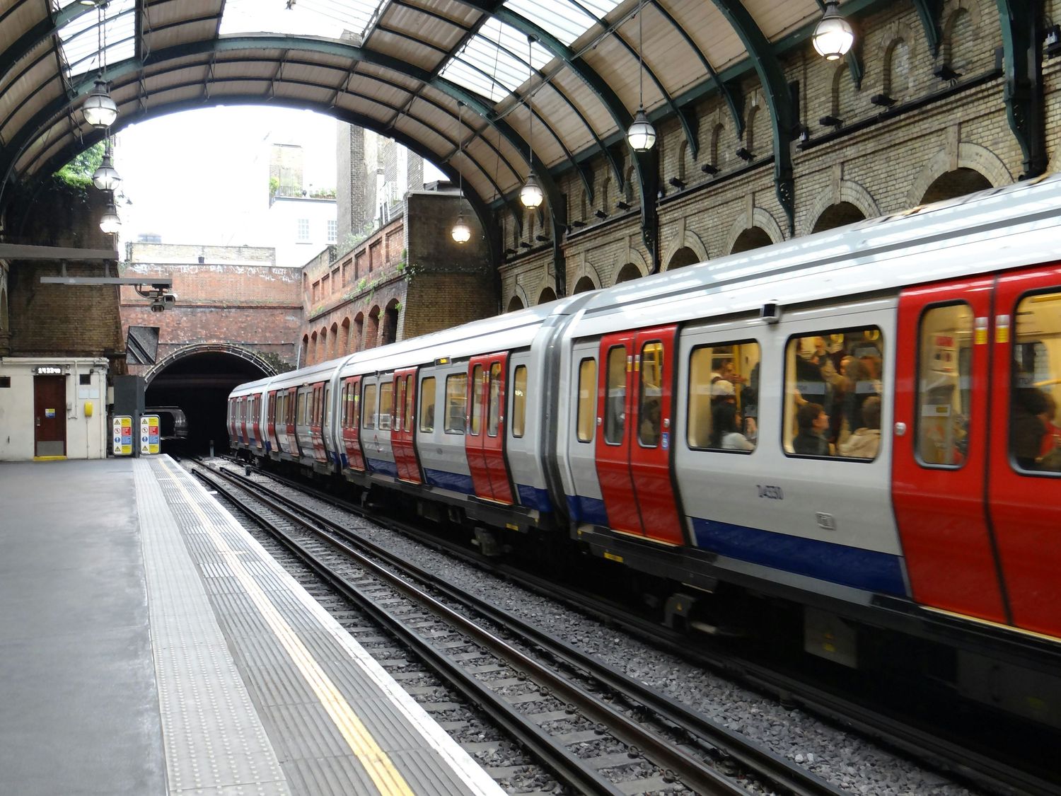 London Underground train platform with curved ceiling and vintage architectural details.
