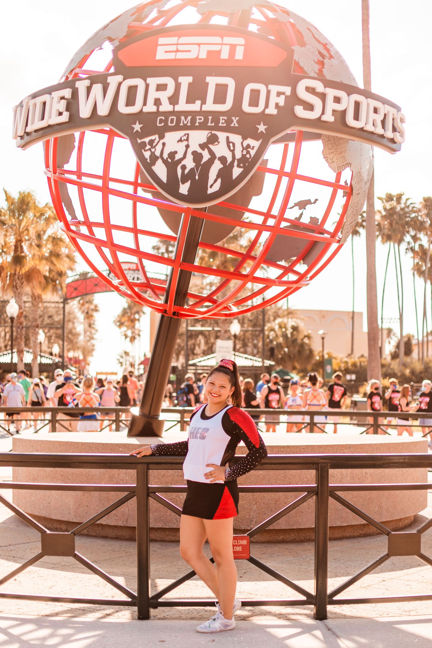 Cheerleader in uniform poses in front of ESPN Wide World of Sports globe sign at Disney.