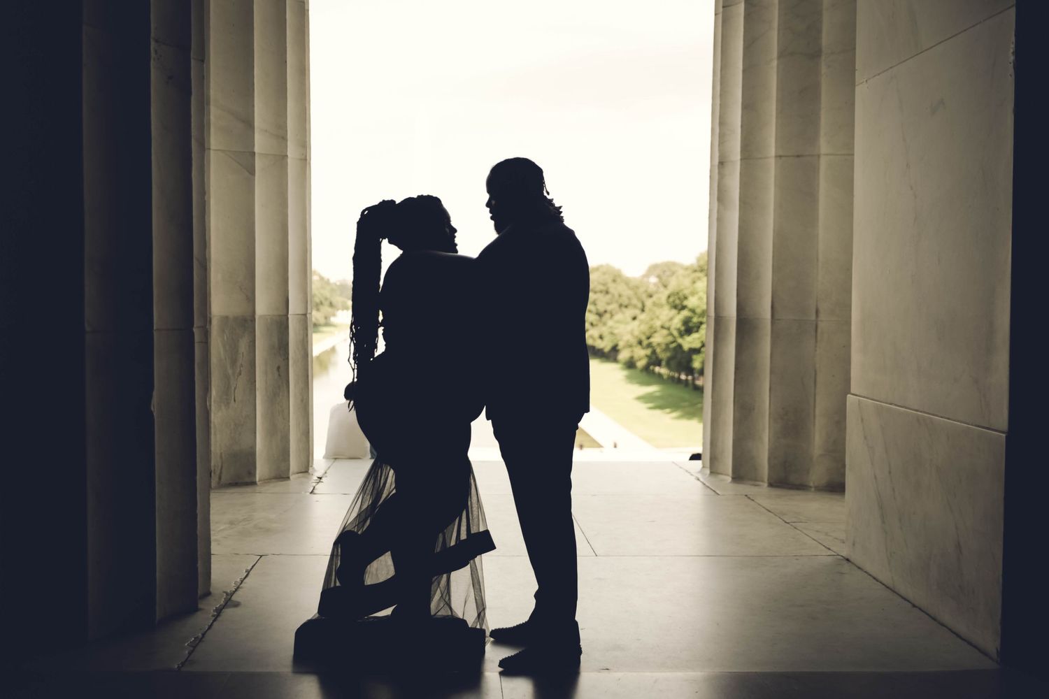 Romantic silhouette of a couple embracing between towering marble columns at the Lincoln Memorial.