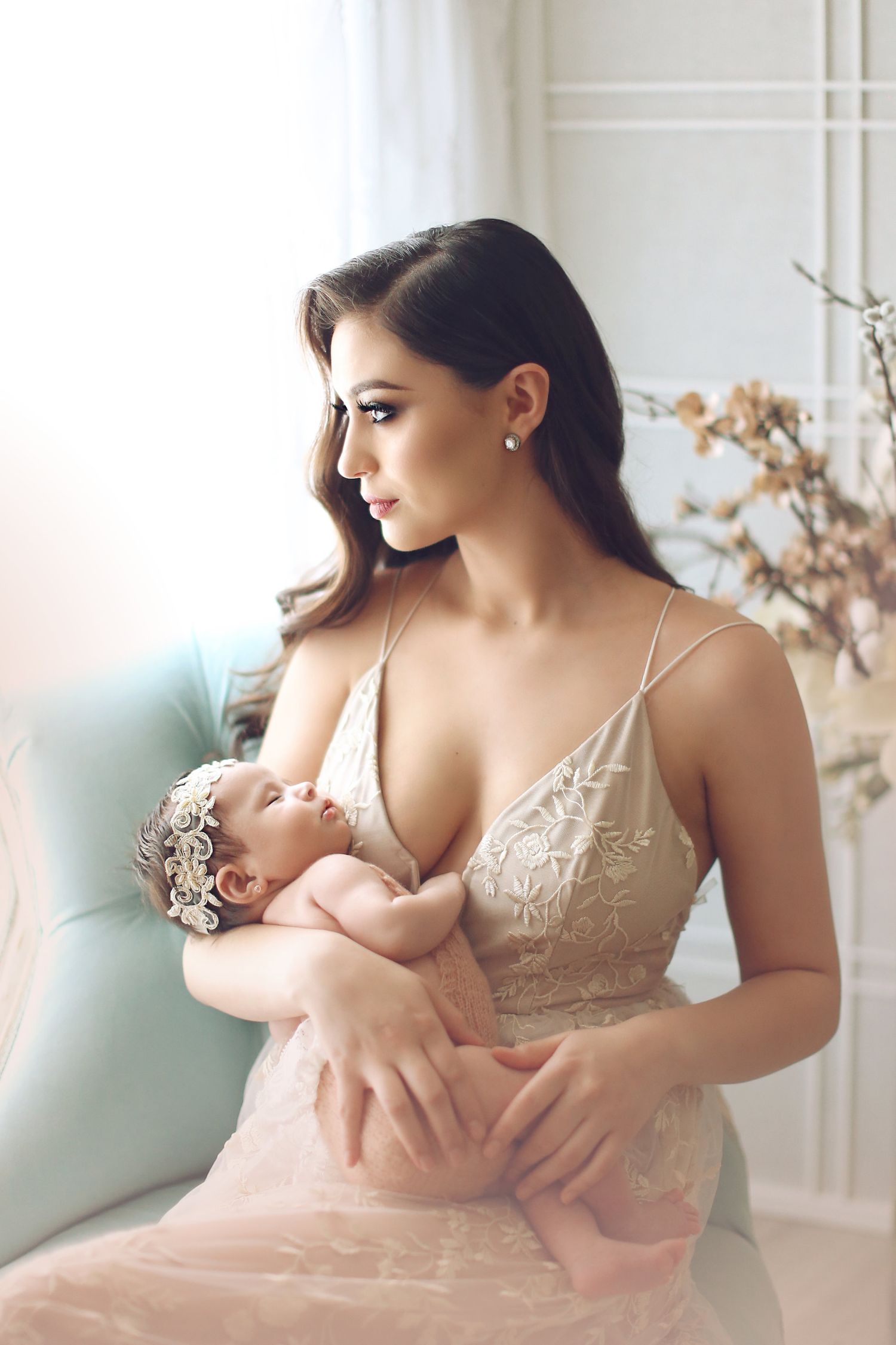 Soft romantic portrait in blush lace dress seated in pastel blue chair.