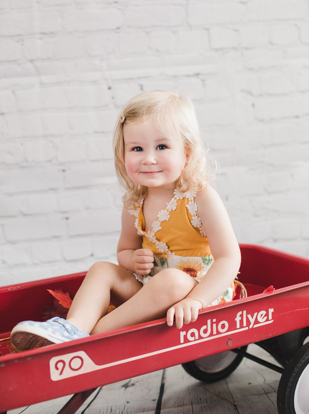 Smiling toddler sitting in a classic red Radio Flyer wagon.