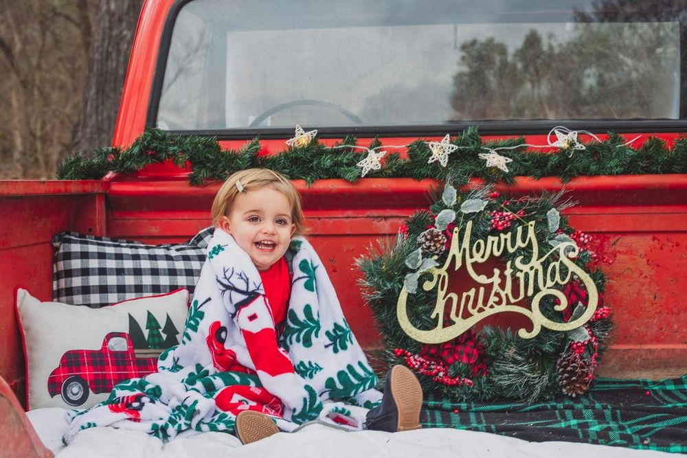 Holiday portraits featuring a red vintage truck decorated for Christmas.