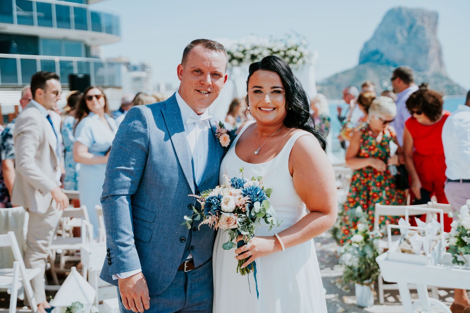Outdoor wedding celebration with scenic coastal backdrop and white ceremony chairs.