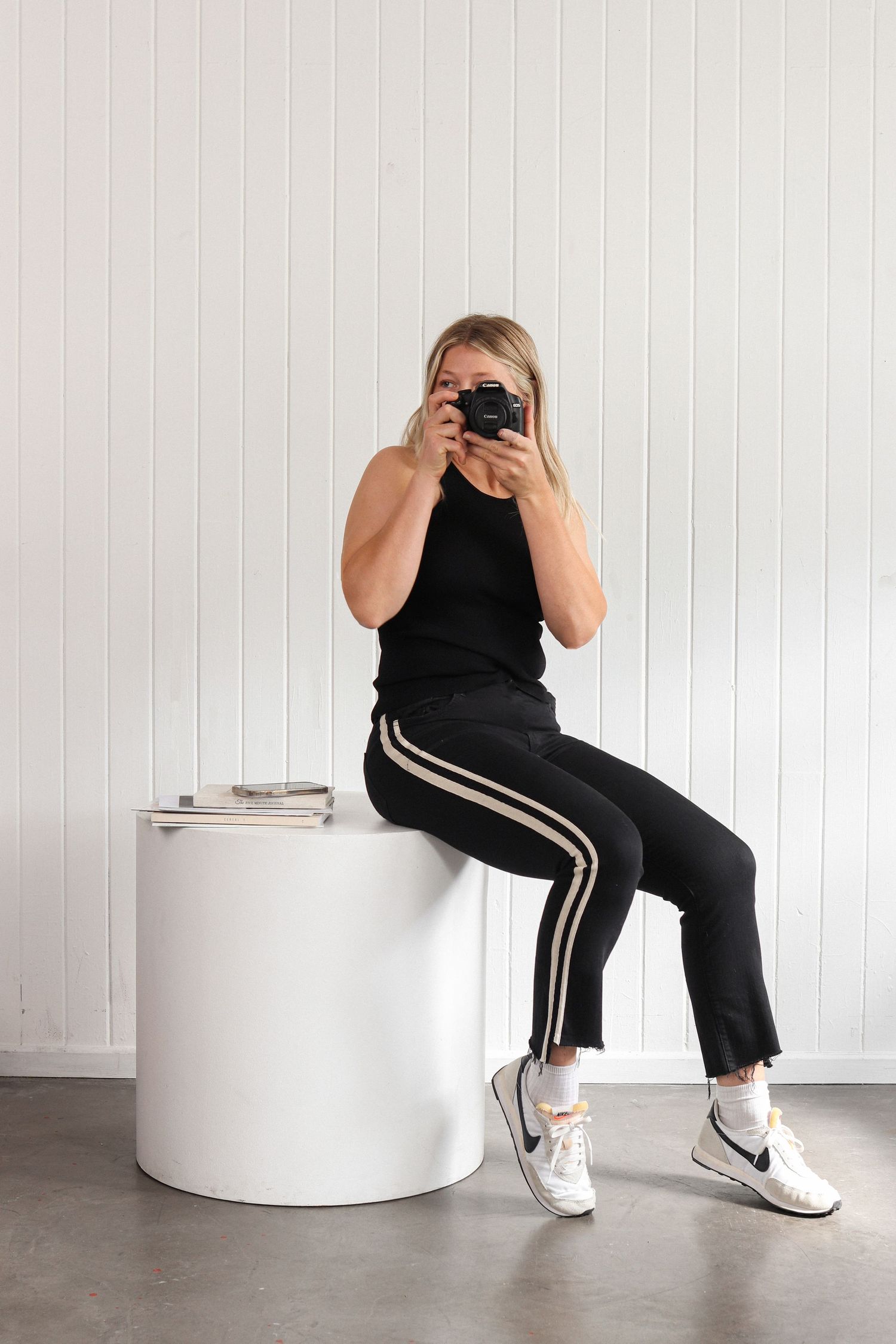 Person in black athleisure outfit sitting on round white ottoman in various poses.