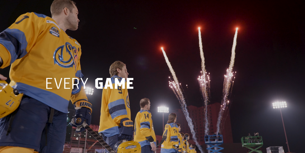 Yellow-uniformed sports team standing before fireworks display at night stadium.