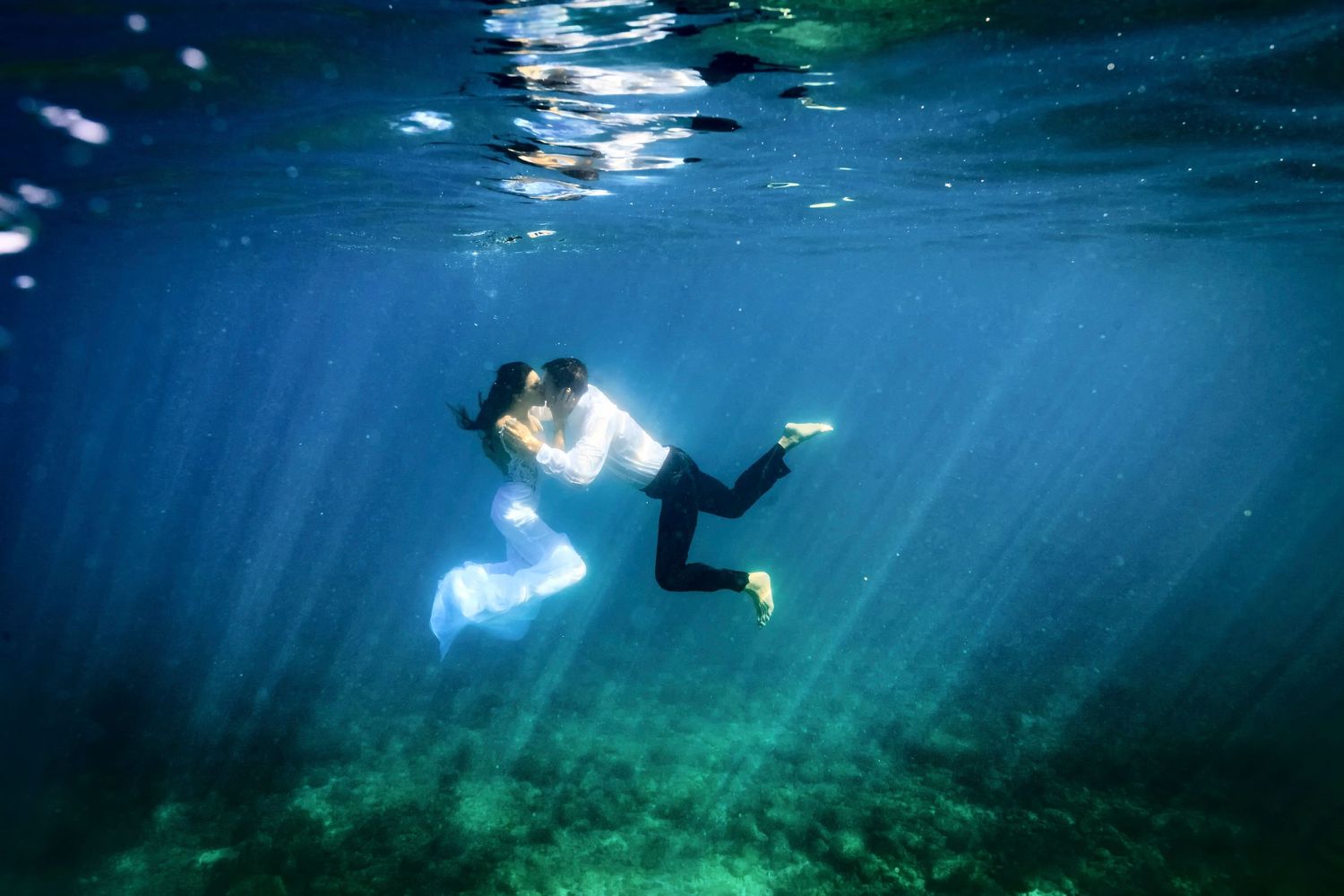 Underwater wedding photography with couple floating in clear blue tropical waters.