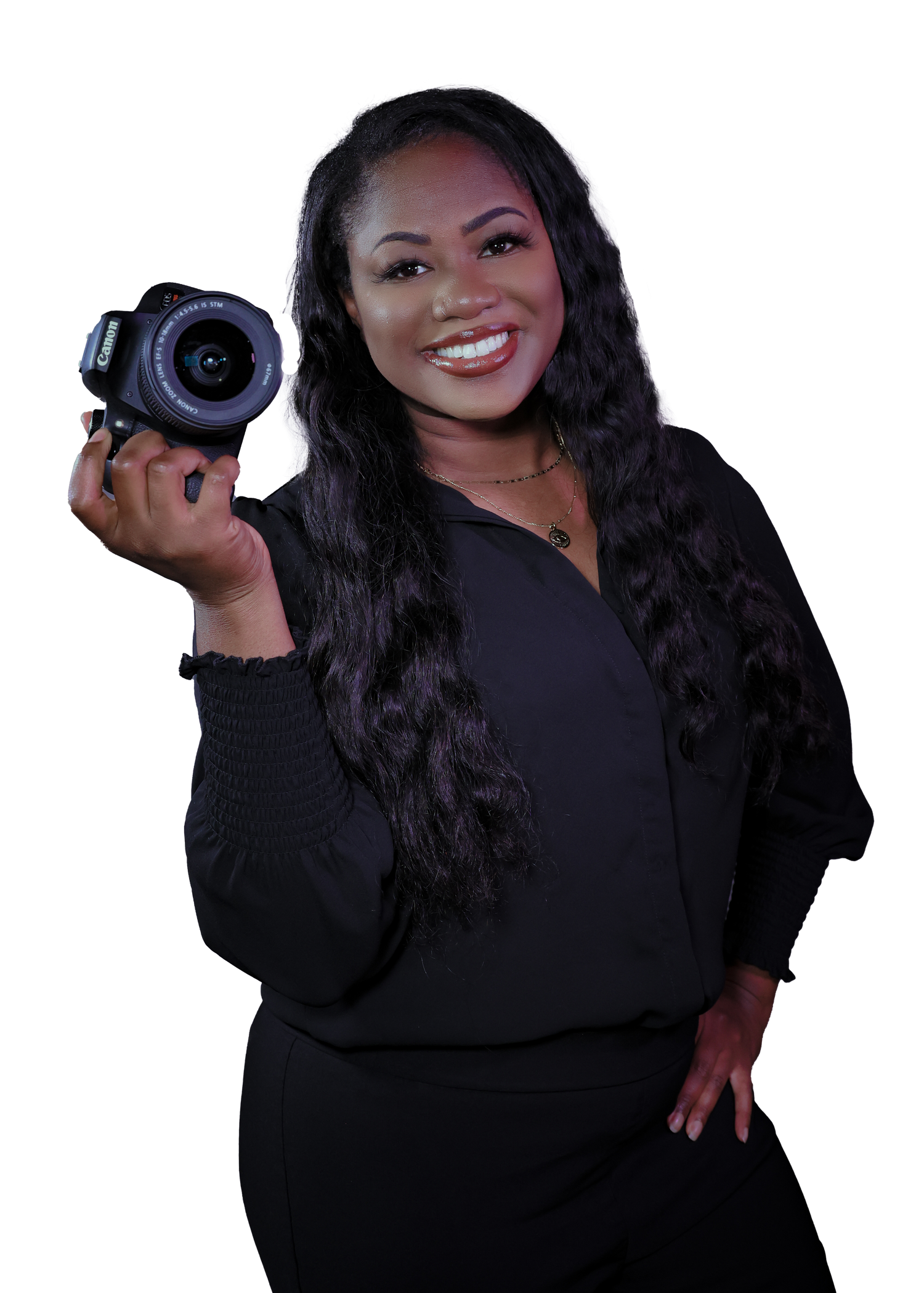 Professional female photographer smiling and holding a DSLR camera wearing an all-black outfit on white background.