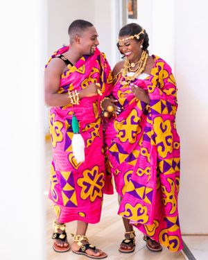 Couple wearing vibrant pink and yellow traditional African print outfits during photo session.