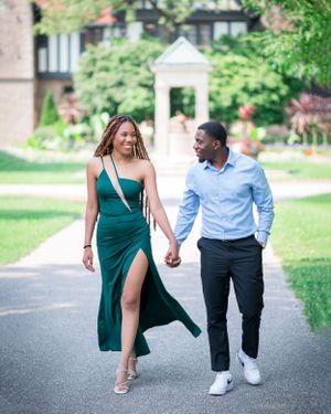 Couple walking hand in hand on path wearing emerald dress and blue shirt during outdoor photo session.