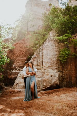 Couple shares intimate moments against a rustic rock wall backdrop in an outdoor photo session.