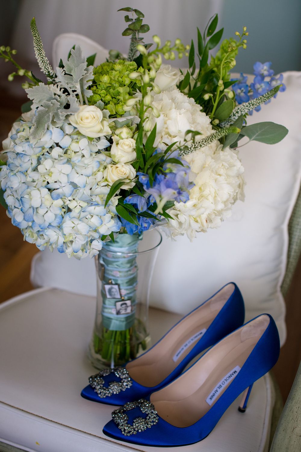 Elegant blue wedding shoes displayed next to a vase of white and blue hydrangea flowers.