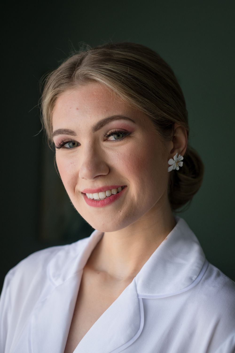 Close up portrait of someone wearing white against dark background.