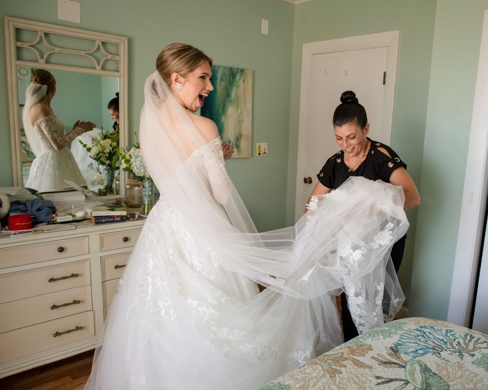 Wedding dress preparation in mint green room with white furniture and mirrors.