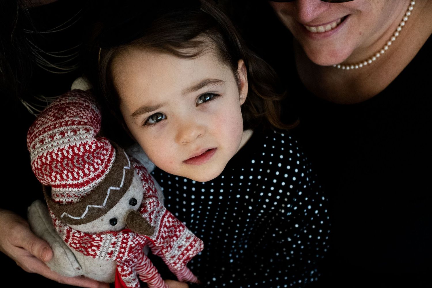 Close-up holiday photo with child holding decorative Christmas doll in polka dot dress.