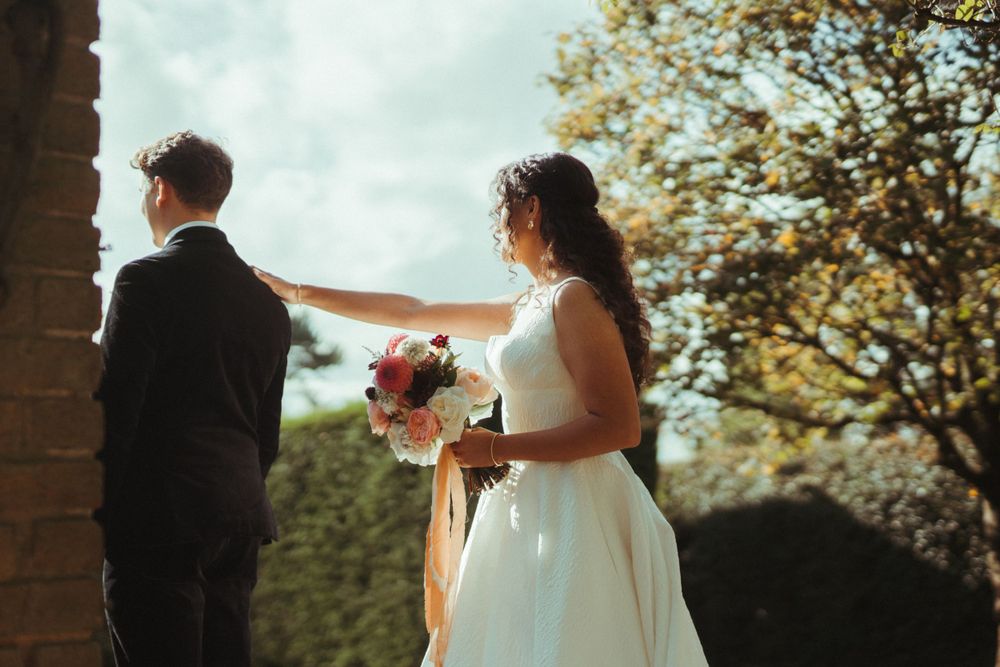 Wedding couple sharing intimate moment by brick archway in garden setting. London Wedding.