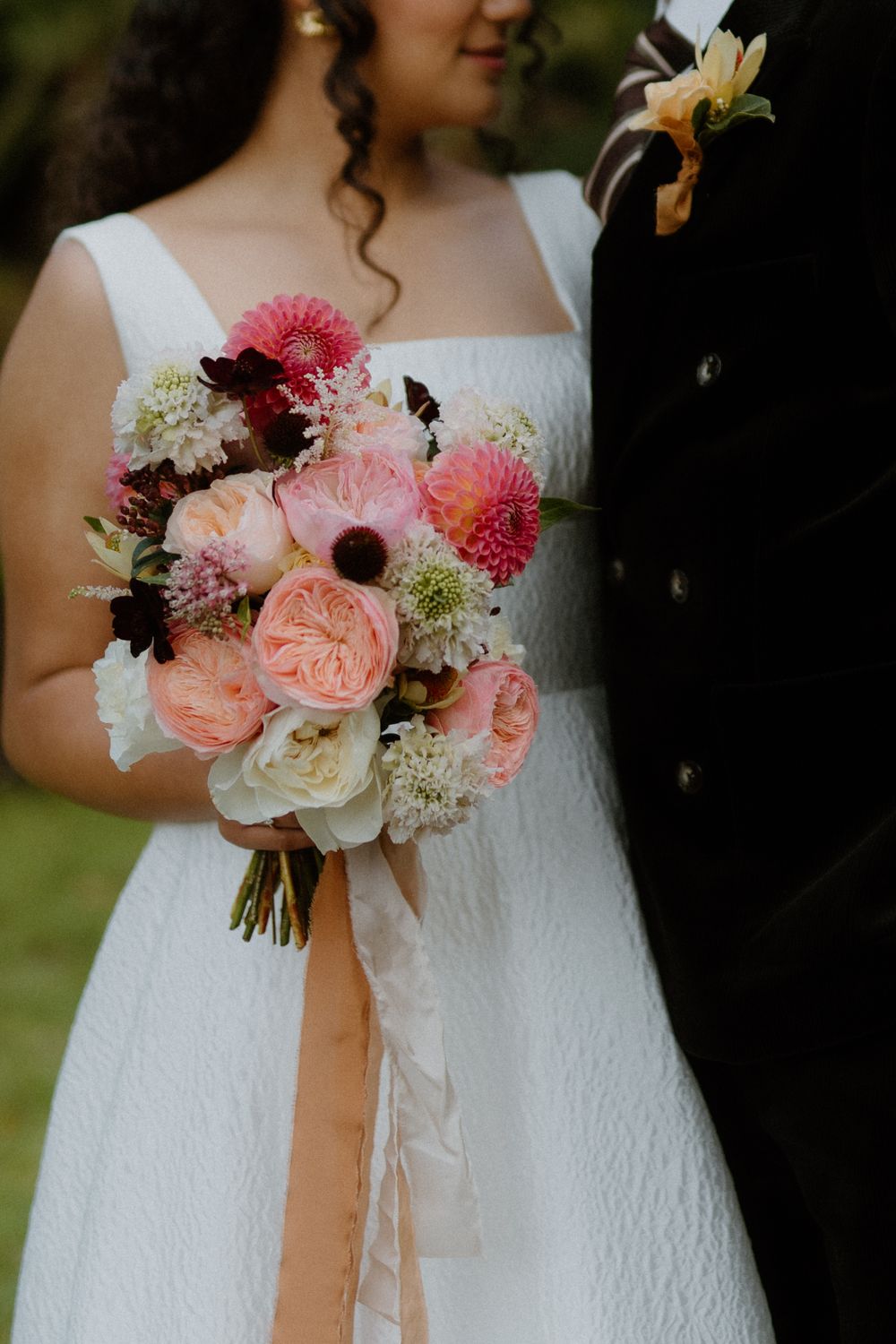 Close-up of a stunning bridal bouquet with pink and white flowers against a white wedding dress. London Wedding.