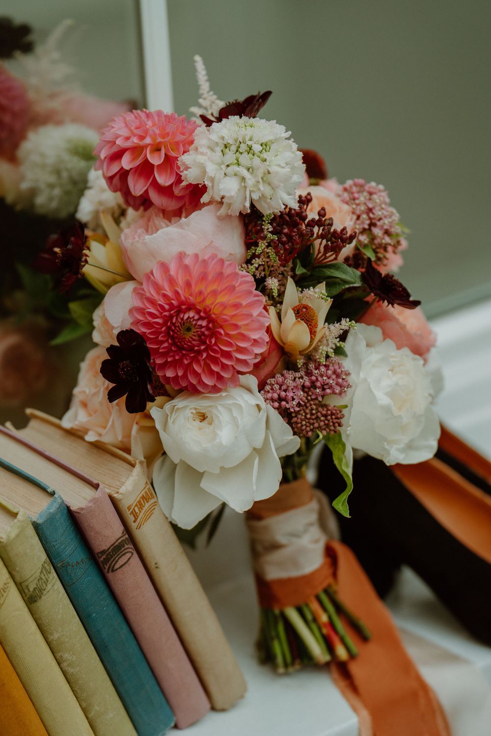 Romantic floral arrangement with pink dahlias and white roses against vintage books. London Wedding.