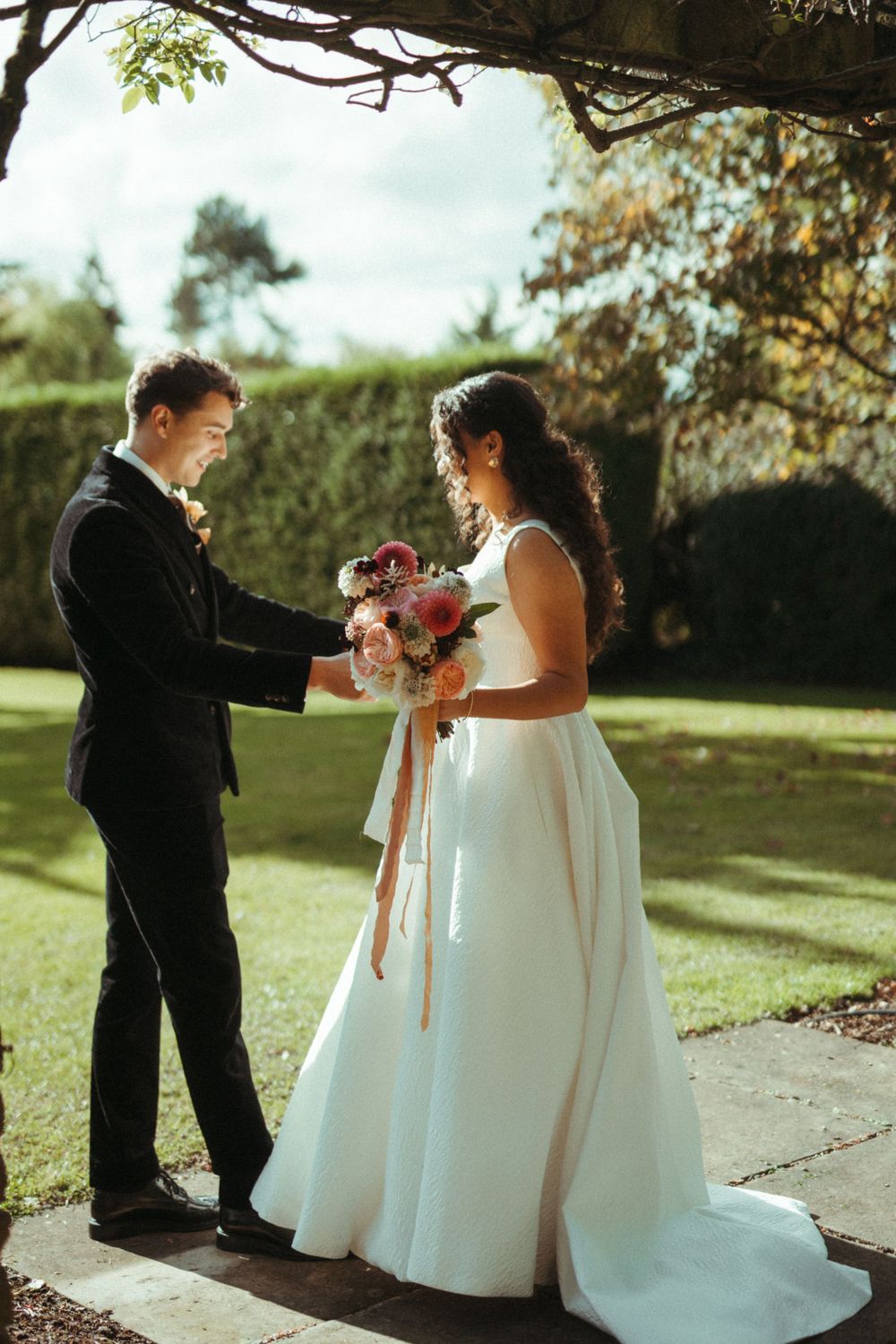 Intimate garden ceremony moment with couple sharing bouquet under brick archway. London Wedding.