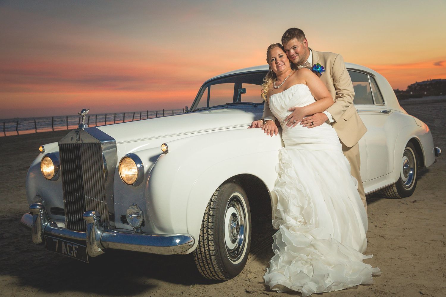 Classic white Rolls Royce on beach at sunset during wedding photoshoot.
