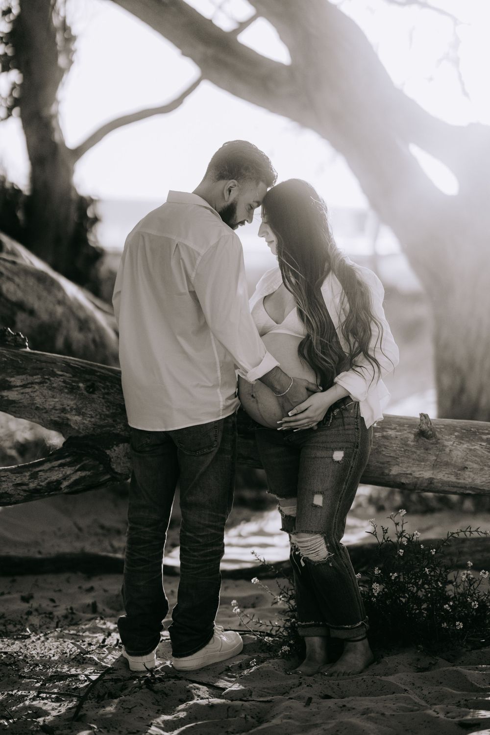 Intimate couple's portrait in foggy forest setting with sunlight filtering through trees.