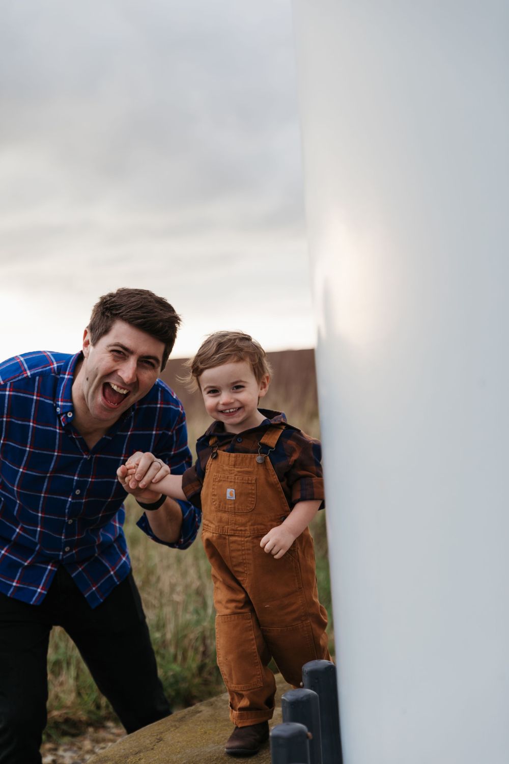 A playful moment shared between two people in blue plaid and brown overalls outdoors.