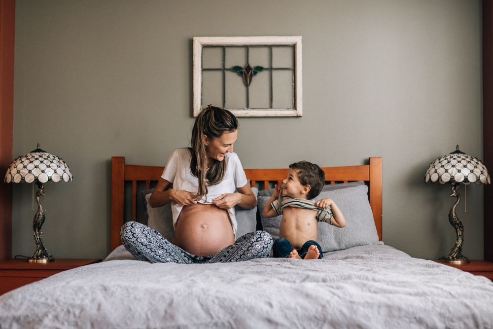 pregnant mom and toddler showing their bellies during maternity  photo shoot in Dubai