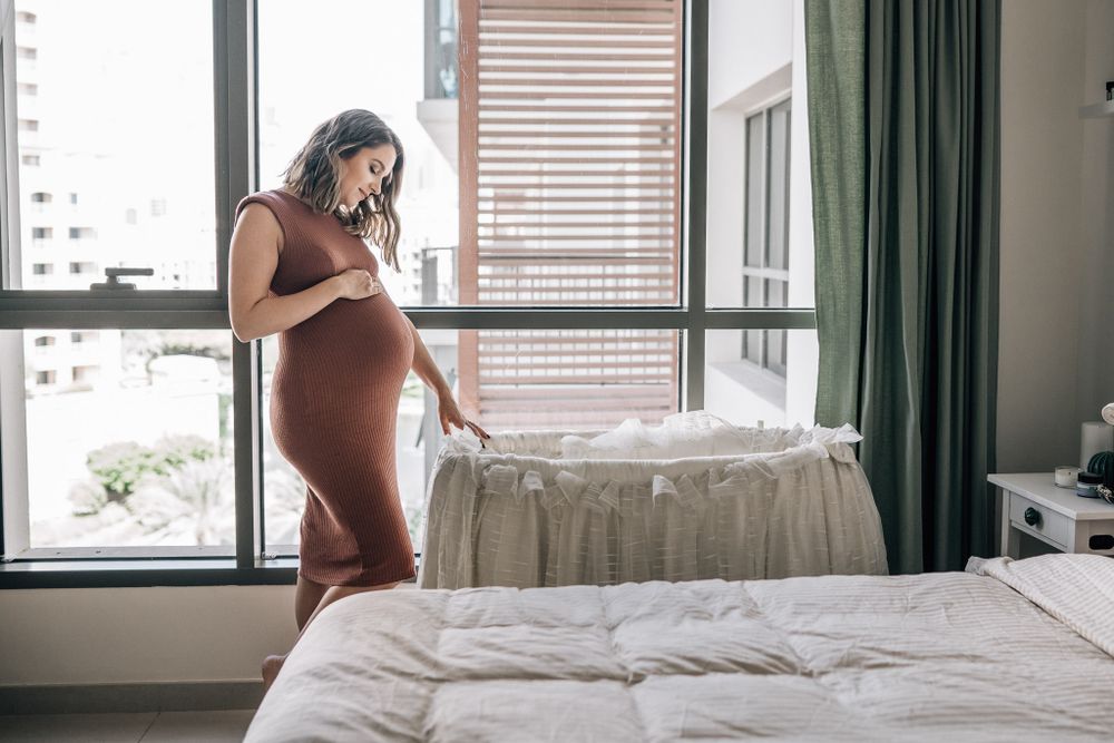 pregnant mother looking at the baby bassinet