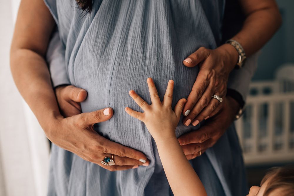 toddler and parents hands on mom's belly during maternity photo shoot in Dubai