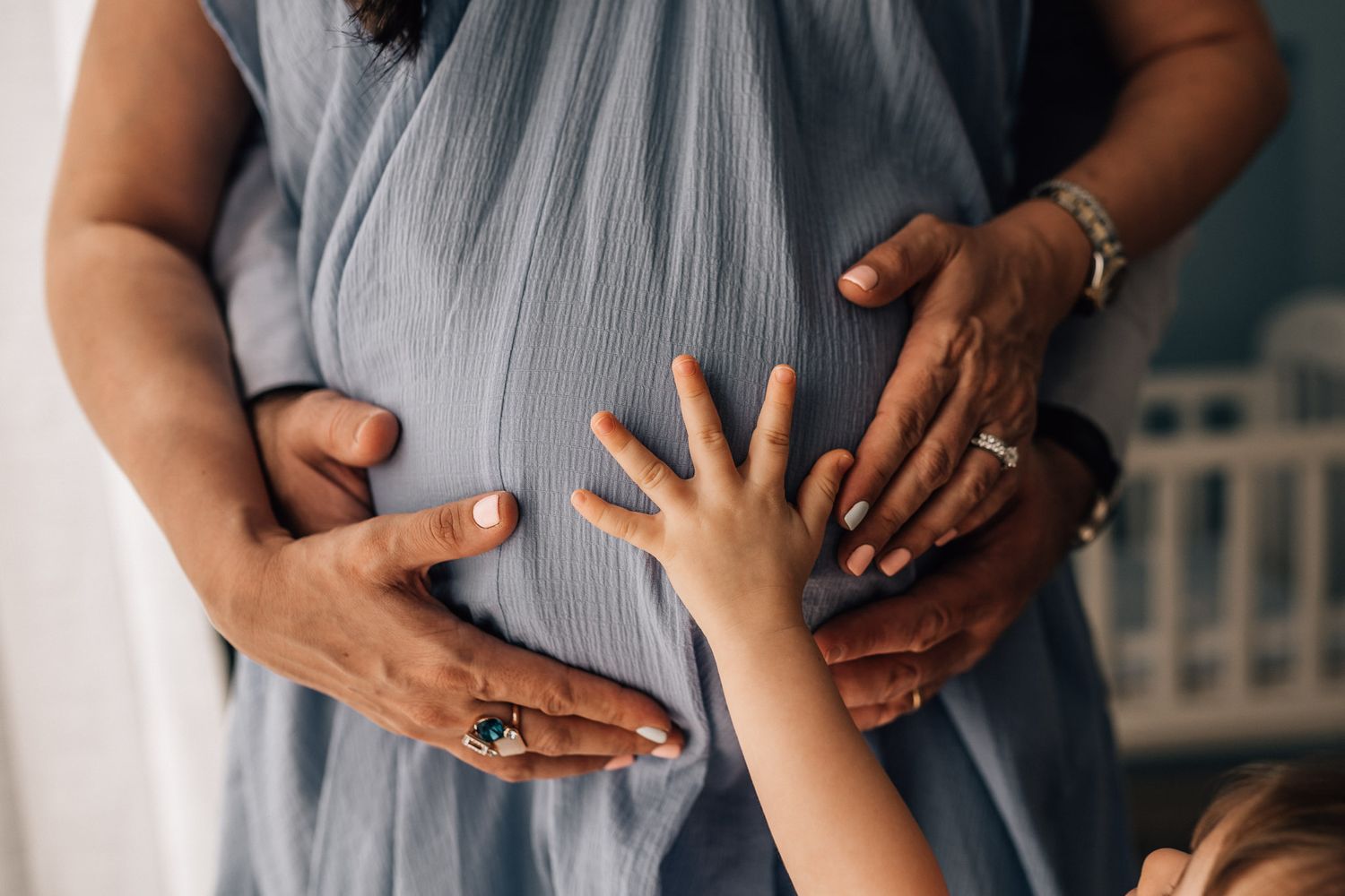 toddler and parents hands on mom's belly during maternity photo shoot in Dubai