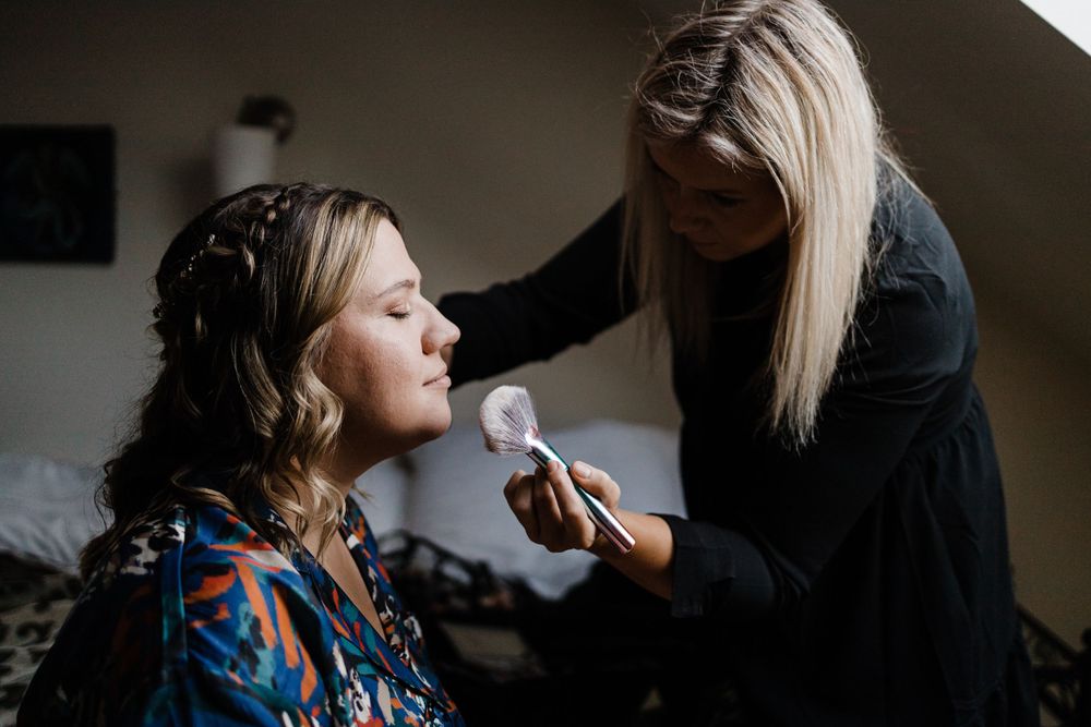 Person applying makeup with a brush in a dimly lit room.